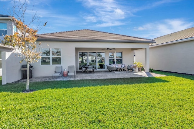 back of property with a ceiling fan, an outdoor hangout area, a yard, and stucco siding