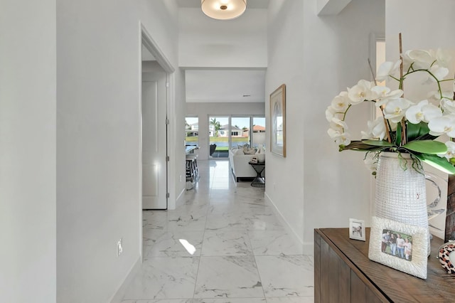 hallway featuring baseboards and light marble finish flooring