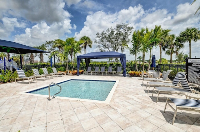 community pool with a gazebo, fence, and a patio