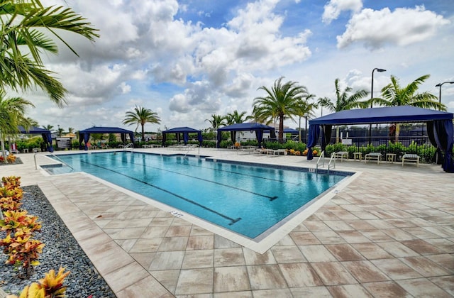 community pool with a gazebo, fence, and a patio area