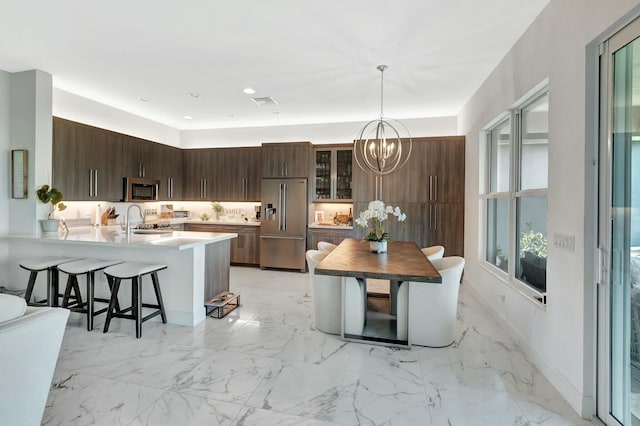 kitchen with appliances with stainless steel finishes, a kitchen bar, a chandelier, a peninsula, and a sink
