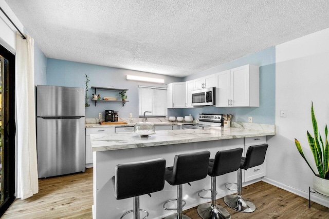 4059 Palm Bay Cir Unit C, West Palm Beach, FL 33406 - kitchen featuring stainless steel appliances, a peninsula, white cabinets, a textured ceiling, and a sink