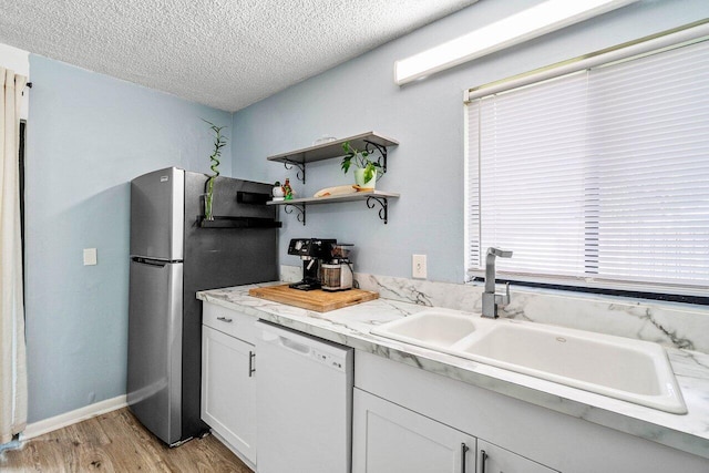 4059 Palm Bay Cir Unit C, West Palm Beach, FL 33406 - kitchen featuring white dishwasher, a sink, a textured ceiling, light wood-type flooring, and light countertops