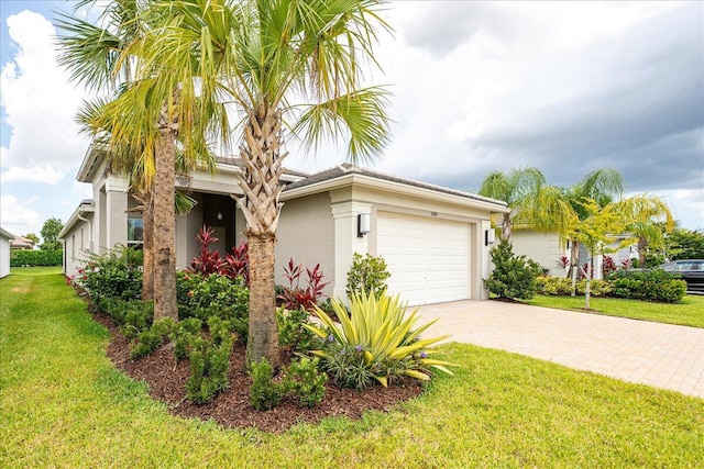 view of front of house featuring stucco siding, driveway, a front lawn, and a garage