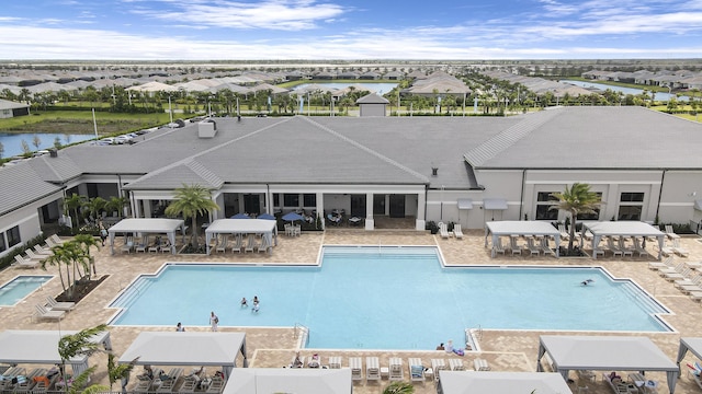 community pool featuring a residential view, a water view, and a patio