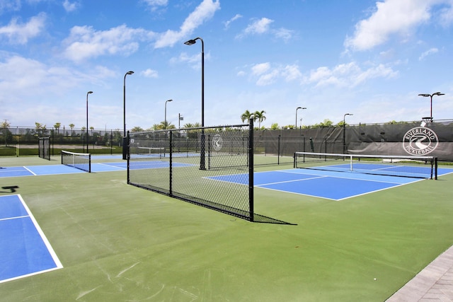 view of tennis court featuring community basketball court and fence