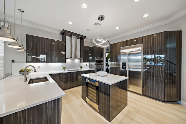 kitchen featuring stainless steel appliances, a sink, wall chimney exhaust hood, modern cabinets, and light countertops