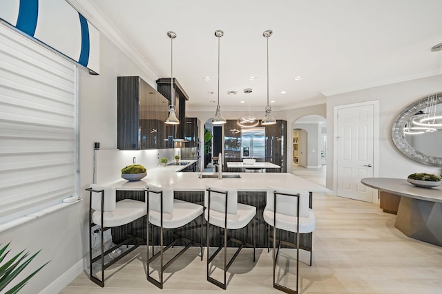 kitchen with arched walkways, light countertops, built in fridge, a peninsula, and a breakfast bar