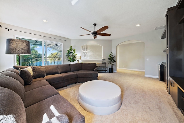 living area with arched walkways, light carpet, recessed lighting, ceiling fan, and baseboards