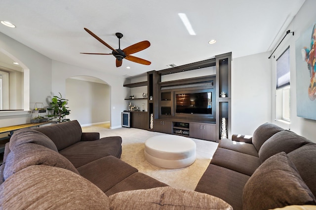 living room featuring arched walkways, a ceiling fan, light carpet, recessed lighting, and baseboards