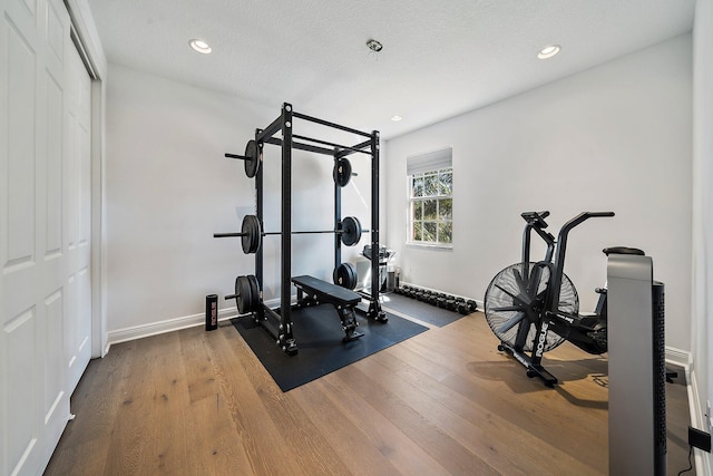 exercise room featuring wood finished floors, recessed lighting, and baseboards
