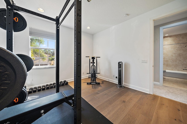 workout room with wood finished floors, recessed lighting, baseboards, and a textured ceiling
