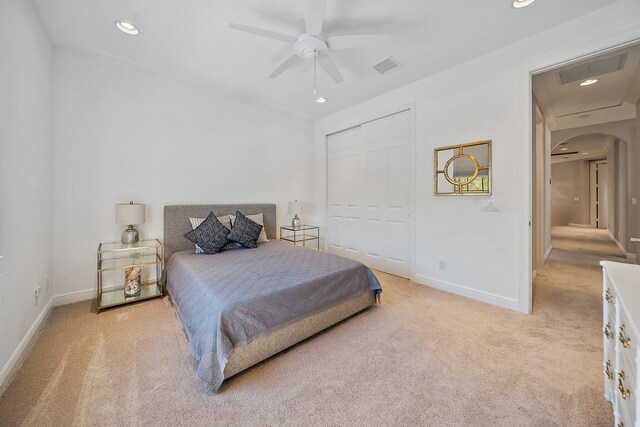bedroom featuring arched walkways, light colored carpet, baseboards, recessed lighting, and a closet