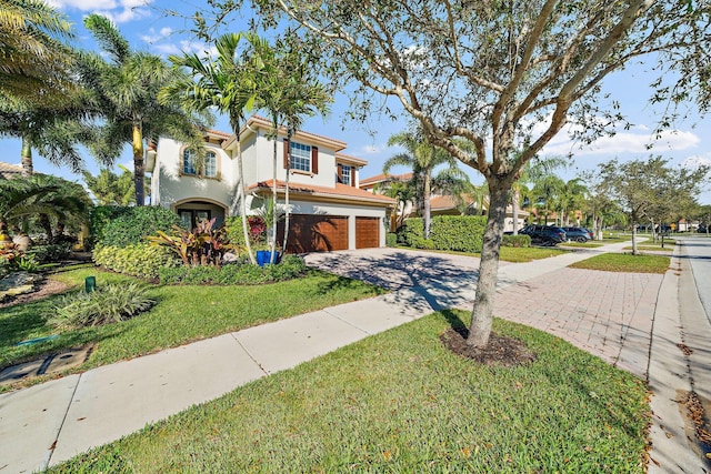 mediterranean / spanish house with driveway, an attached garage, stucco siding, and a front lawn