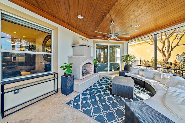 living area featuring wood ceiling, a ceiling fan, ornamental molding, a tiled fireplace, and stone tile floors