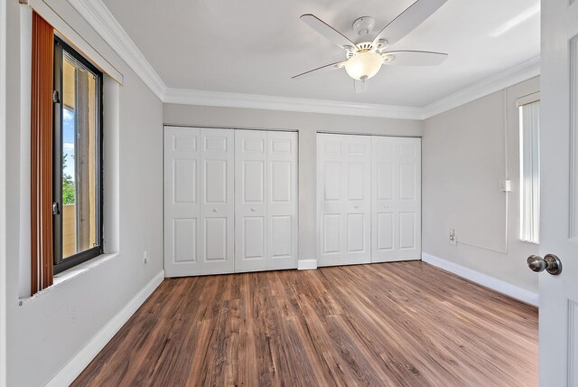 5393 SE Miles Grant Rd Unit A203, Stuart, FL 34997 - unfurnished bedroom featuring two closets, baseboards, dark wood finished floors, ornamental molding, and a ceiling fan