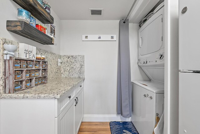 5393 SE Miles Grant Rd Unit A203, Stuart, FL 34997 - laundry area with stacked washer and clothes dryer, baseboards, and light wood-type flooring