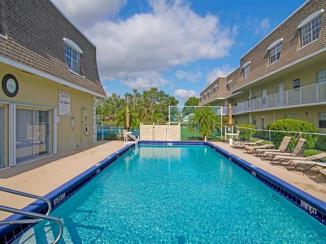 community pool with a patio and fence