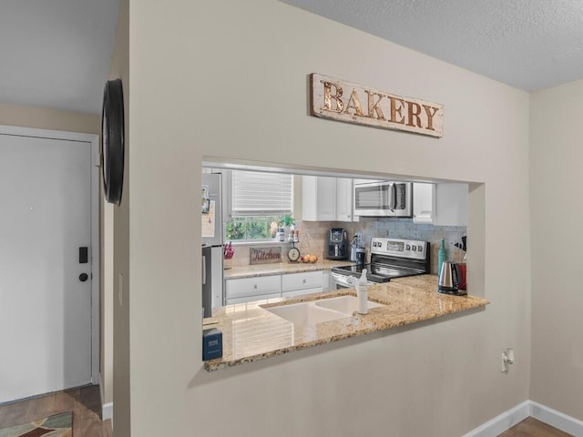 kitchen with stainless steel appliances, decorative backsplash, white cabinetry, baseboards, and light stone countertops