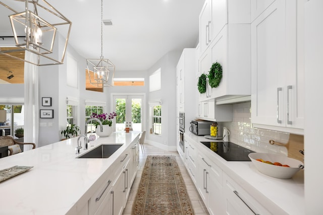 kitchen featuring a sink, a chandelier, black appliances, white cabinetry, and french doors