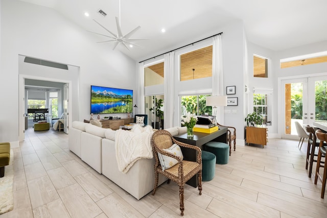 living area featuring high vaulted ceiling, french doors, a ceiling fan, healthy amount of natural light, and light wood-style floors
