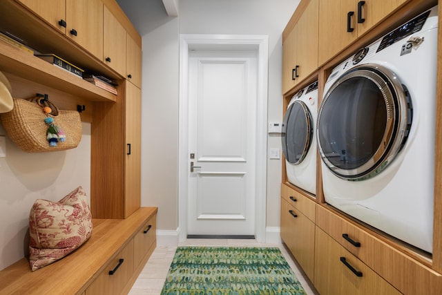 clothes washing area featuring washing machine and dryer and cabinet space