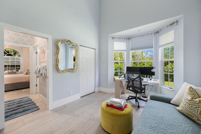 office with wood finished floors, baseboards, and a high ceiling