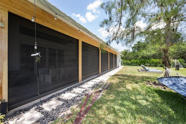 view of side of home with a sunroom and a lawn