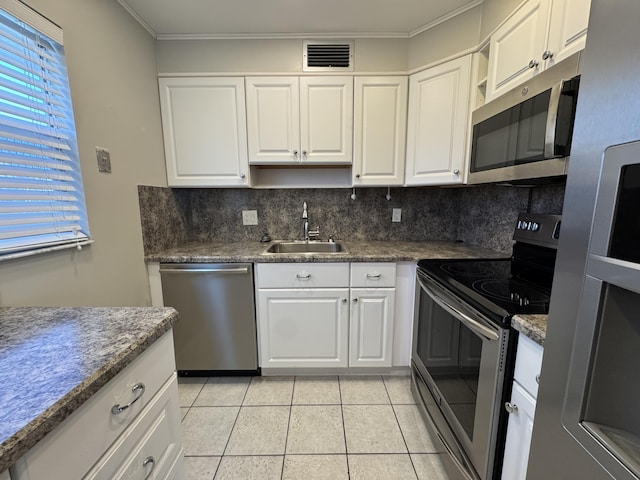 kitchen with stainless steel appliances, a sink, tasteful backsplash, light tile patterned floors, and white cabinets
