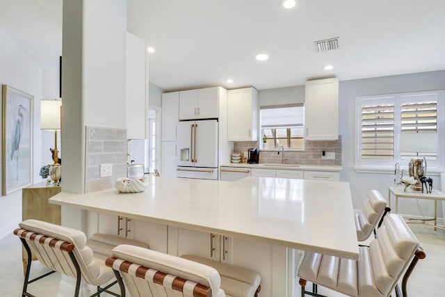 5021 Magnolia Bay Cir, Palm Beach Gardens, FL 33418 - kitchen featuring white appliances, a peninsula, backsplash, white cabinets, and recessed lighting