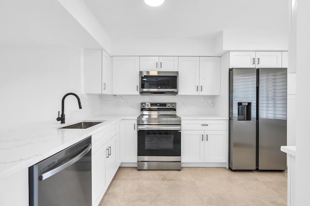 kitchen featuring stainless steel appliances, a sink, white cabinetry, and light stone counters