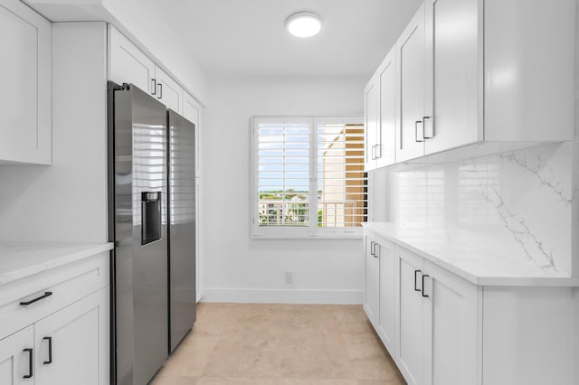 kitchen featuring stainless steel fridge with ice dispenser, baseboards, backsplash, white cabinets, and light stone countertops