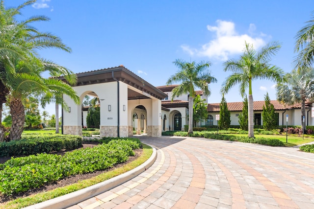 8640 E Baypoint Cir, Parkland, FL 33076 - mediterranean / spanish house featuring stucco siding, stone siding, a tiled roof, and curved driveway