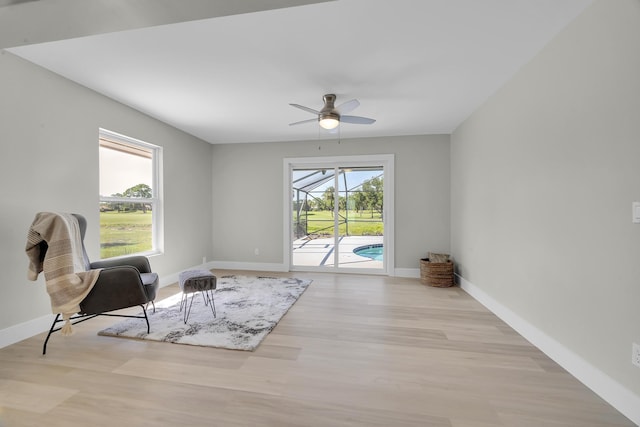 sitting room with a ceiling fan, wood finished floors, baseboards, and a sunroom