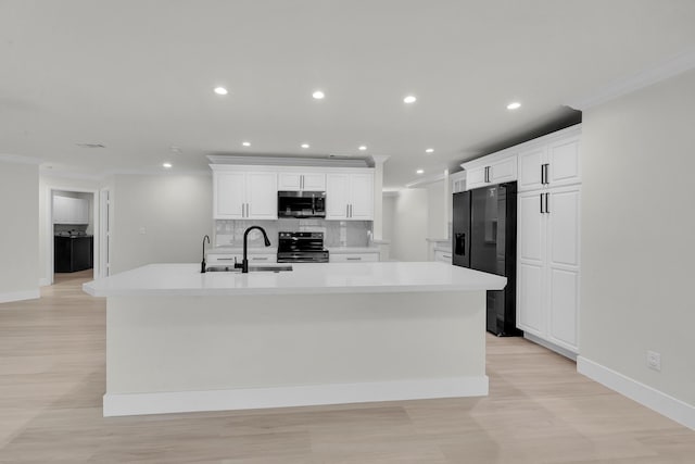 kitchen with stainless steel appliances, a sink, light wood-type flooring, tasteful backsplash, and a large island