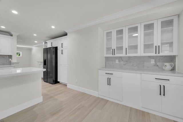 kitchen featuring black refrigerator with ice dispenser, light wood-type flooring, recessed lighting, crown molding, and decorative backsplash