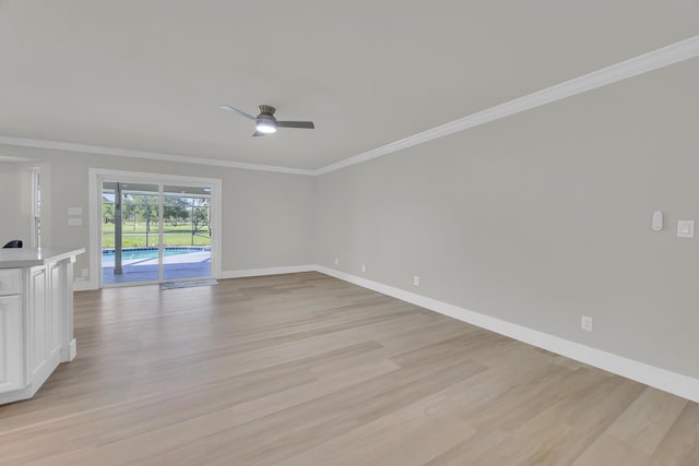spare room featuring light wood-style flooring, baseboards, crown molding, and ceiling fan