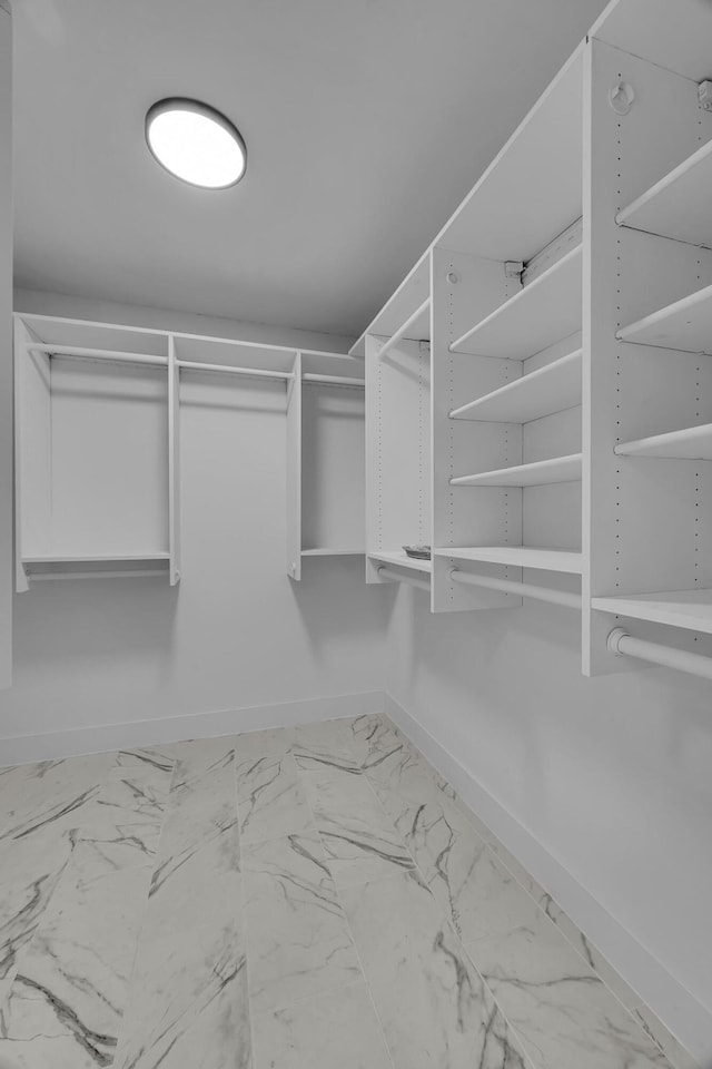 walk in closet featuring marble look tile flooring