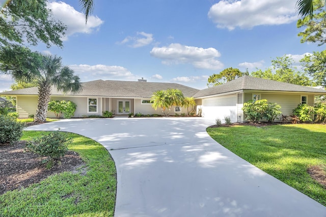 ranch-style house with french doors, driveway, an attached garage, and a front lawn