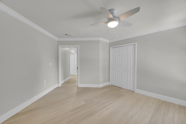 unfurnished bedroom featuring light wood-style flooring, ornamental molding, baseboards, a closet, and a ceiling fan