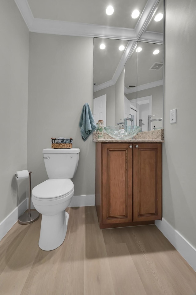 bathroom featuring ornamental molding, wood finished floors, baseboards, toilet, and vanity