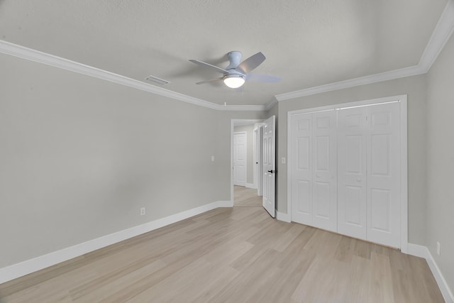 unfurnished bedroom with light wood finished floors, a closet, baseboards, crown molding, and a ceiling fan