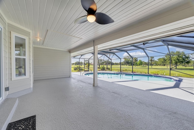 swimming pool featuring a patio area, a ceiling fan, glass enclosure, and a yard