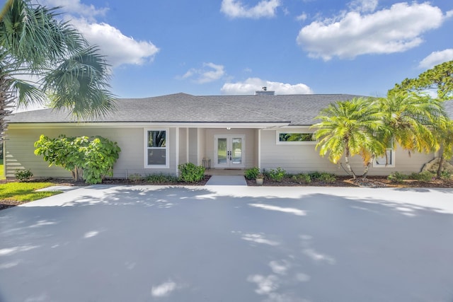 single story home featuring french doors and roof with shingles