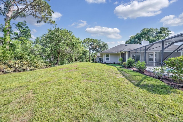 view of grassy yard with a lanai and a patio area