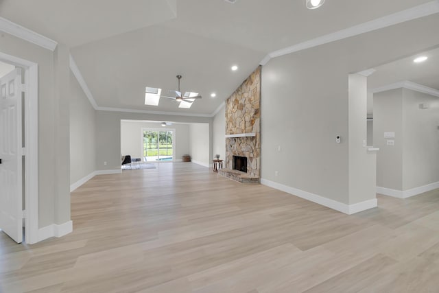 unfurnished living room with ornamental molding, light wood finished floors, a stone fireplace, a skylight, and baseboards