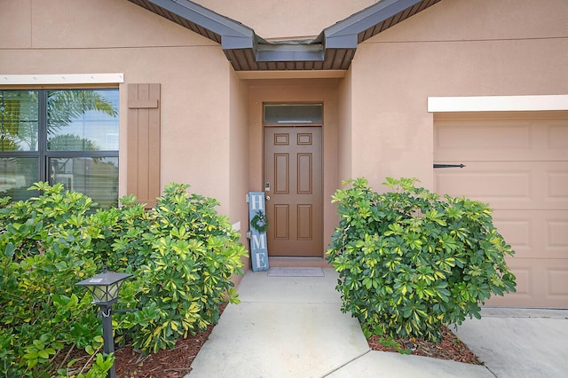 6241 NW Regent St, Port Saint Lucie, FL 34983 - property entrance with stucco siding and an attached garage