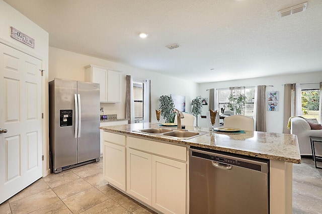 6241 NW Regent St, Port Saint Lucie, FL 34983 - kitchen featuring appliances with stainless steel finishes, open floor plan, an island with sink, a sink, and light stone counters