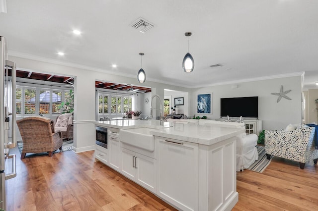 605 Flotilla Ln, North Palm Beach, FL 33408 - kitchen with built in microwave, a sink, open floor plan, ornamental molding, and white cabinetry