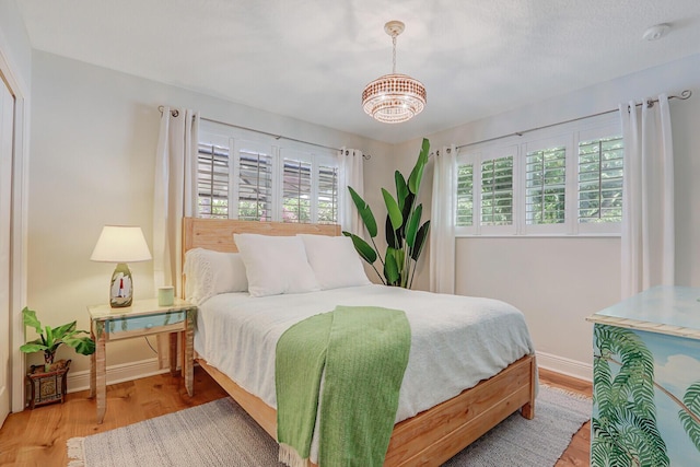 605 Flotilla Ln, North Palm Beach, FL 33408 - bedroom featuring multiple windows, a chandelier, wood finished floors, and baseboards